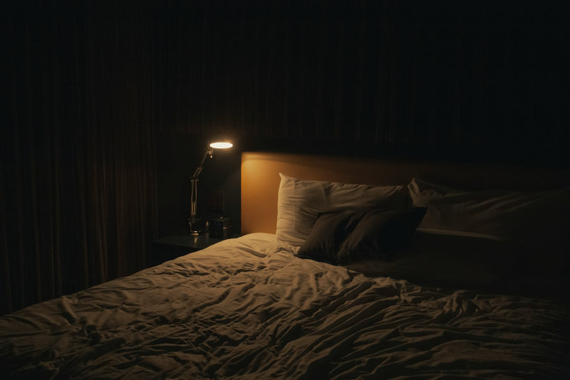A warm bedside lamp glowing in a dark bedroom